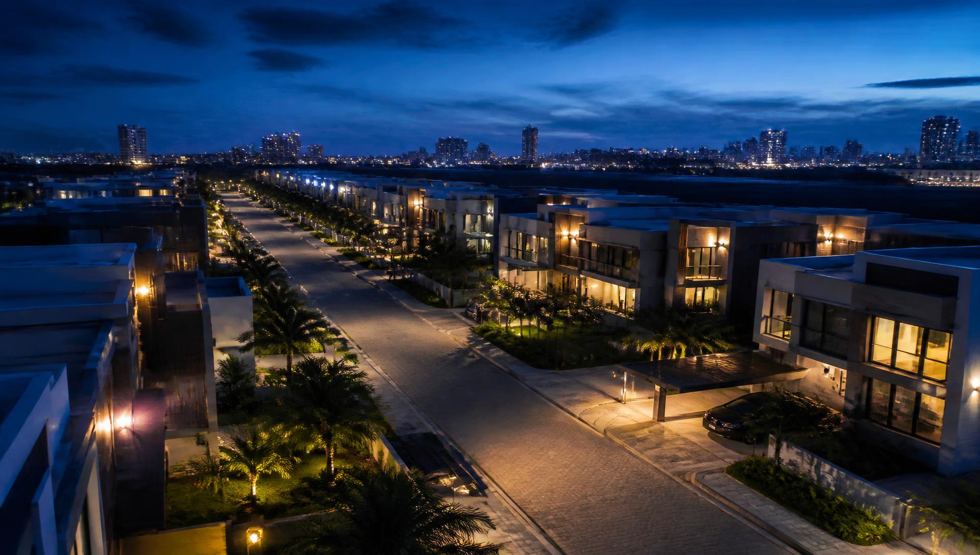 Aerial view at dusk of a planned residential estate with lit terraces and landscaped roads